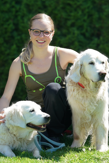 Amélie Jampen sitzt mit zwei Golden Retriever im Garten der Klinik